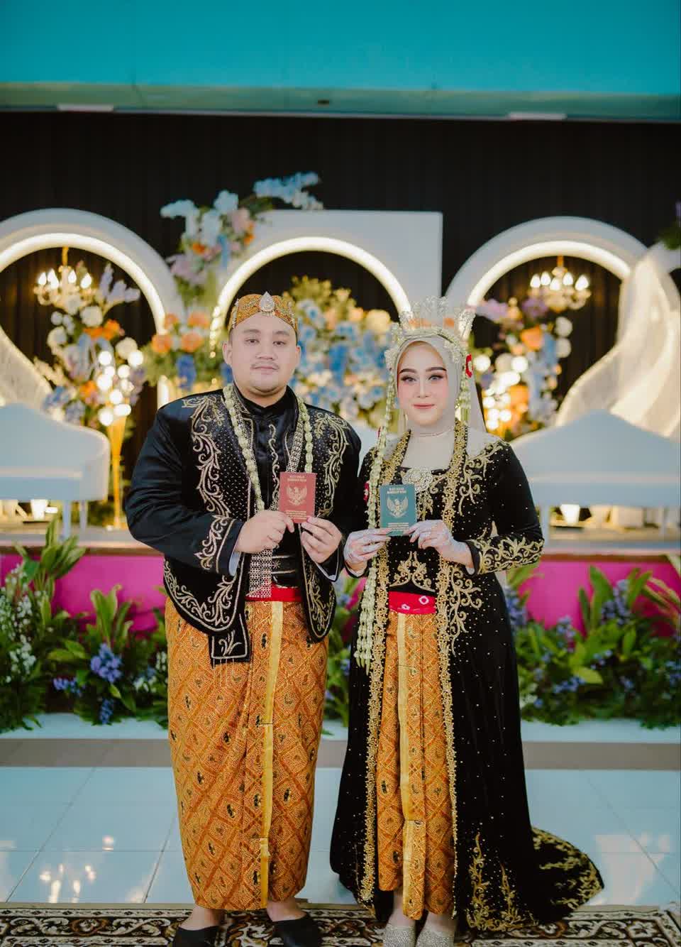 Pengantin memegang buku nikah di pelaminan